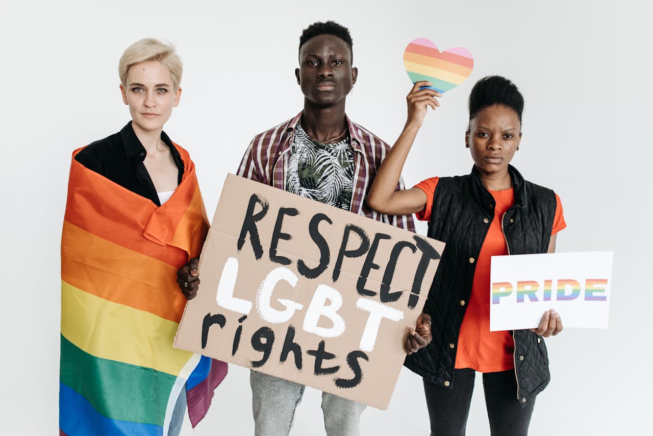 A diverse group of people standing for LGBT rights, holding pride signs.