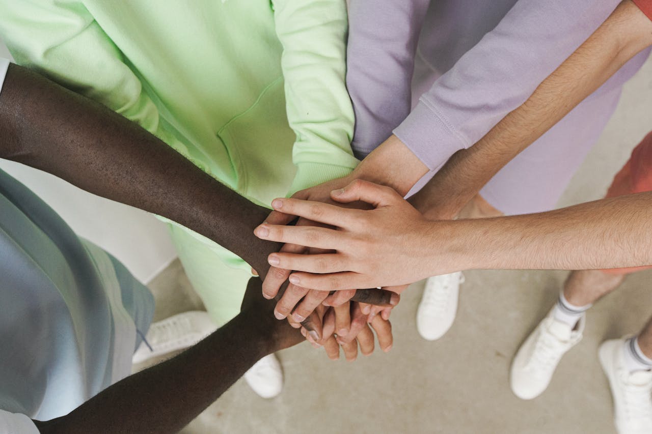 Mastering the First Impression: Your intriguing post title goes here Top view of diverse hands stacked together, symbolizing unity and teamwork.